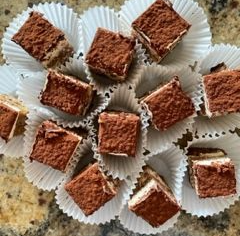 A chocolate cake with nuts on top is on a cutting board with a fork.