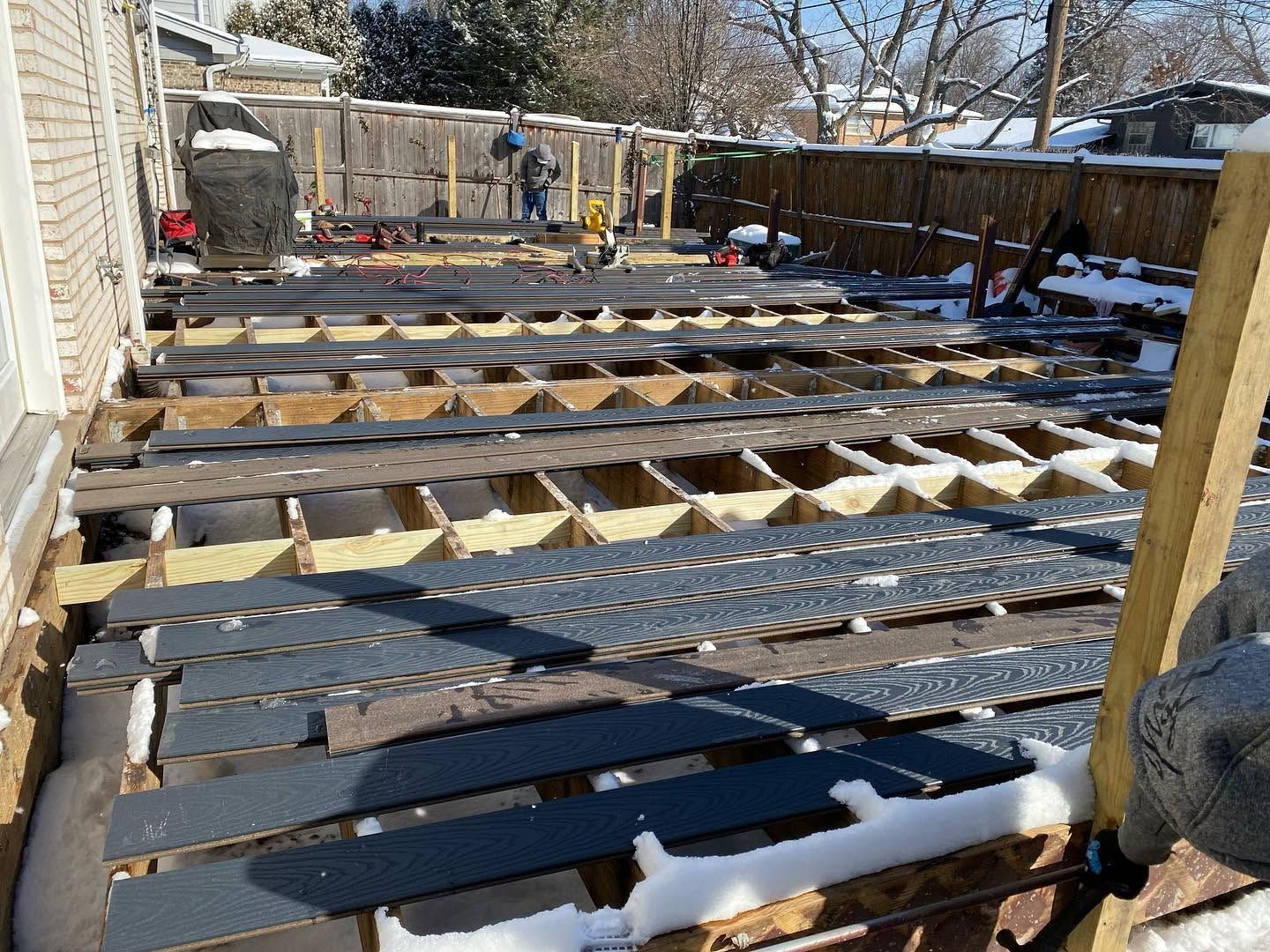 Partially built wooden deck frame with snow patches in a backyard