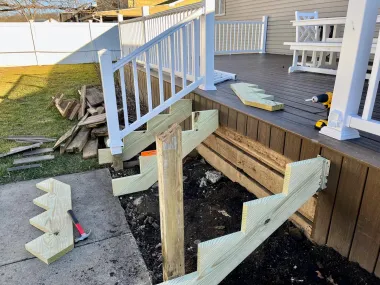Damaged wooden deck stairs with broken railings and scattered boards in a backyard.