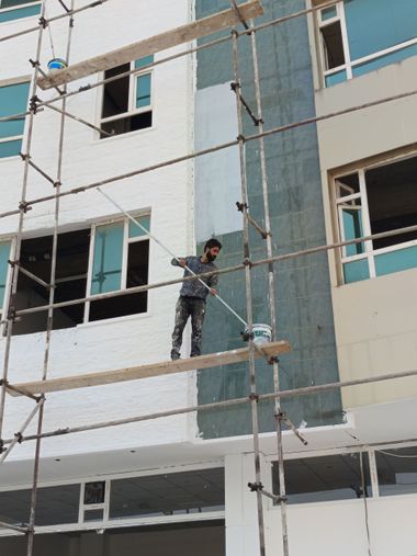 Worker on scaffolding beside a building exterior during construction or maintenance