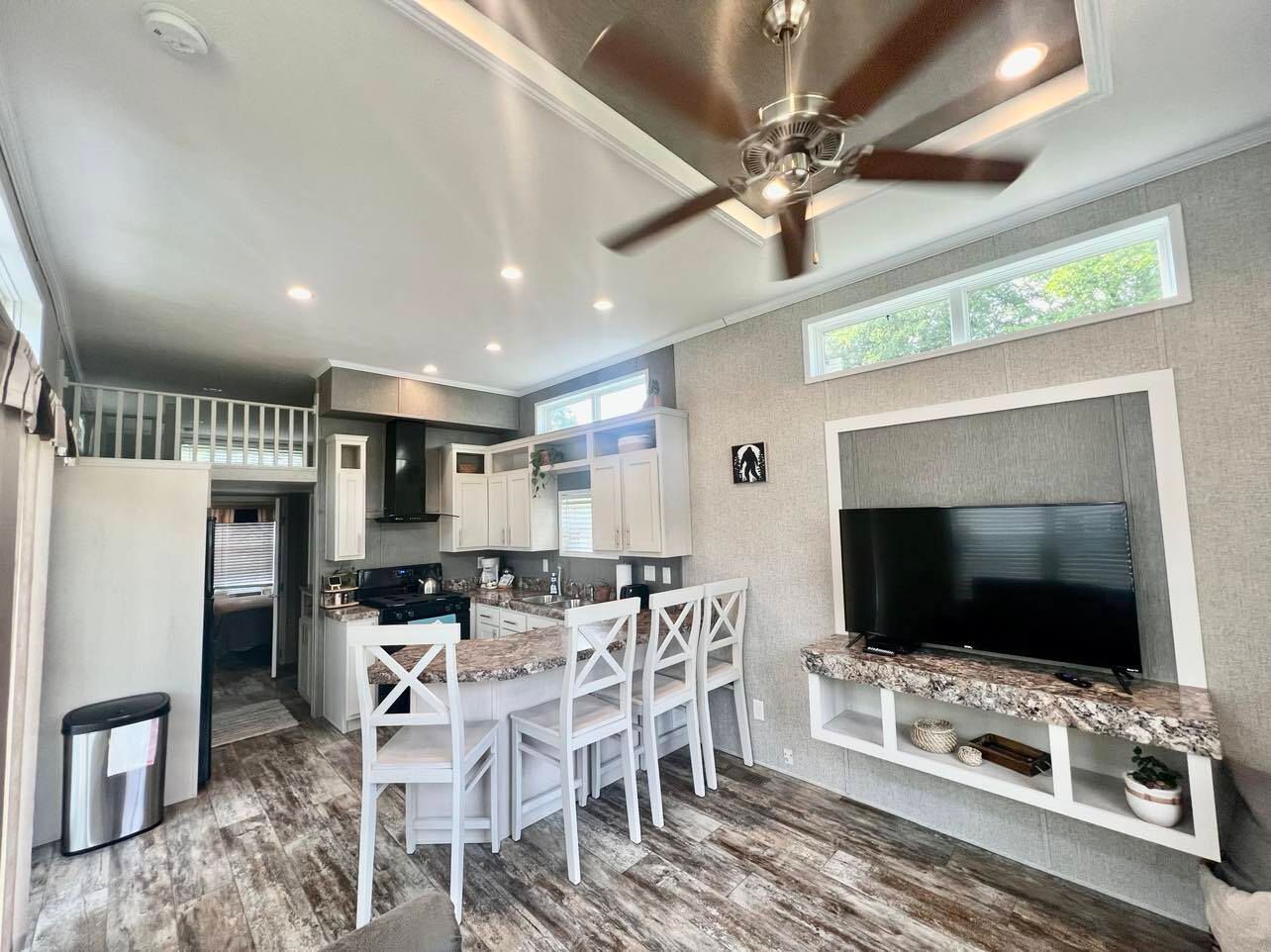 a kitchen with a ceiling fan and a flat screen tv