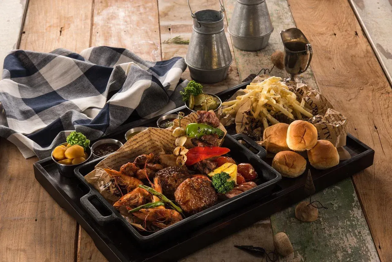 a tray of bbq food with french fries and bread on a wooden table
