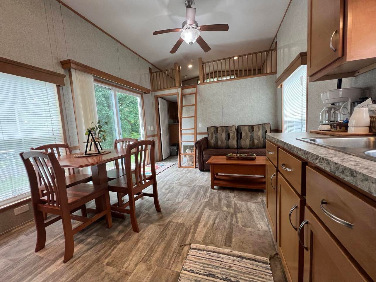 a living room with a table and chairs and a ceiling fan