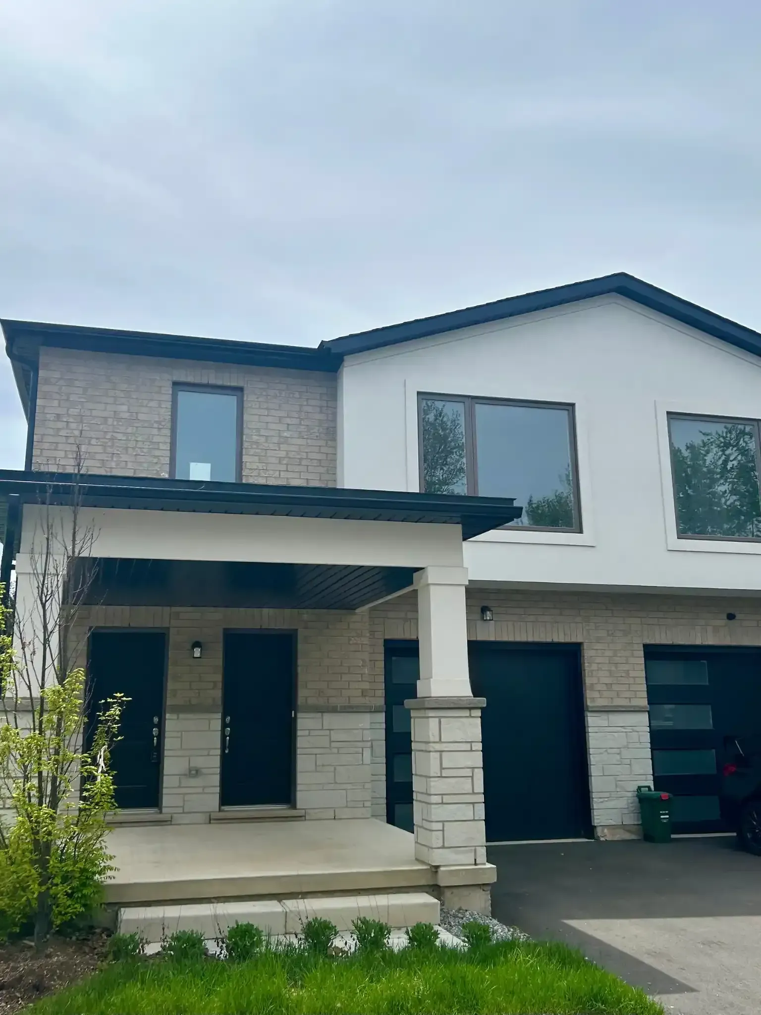 Exterior view of a house with columns and a dark roof under an overcast sky.