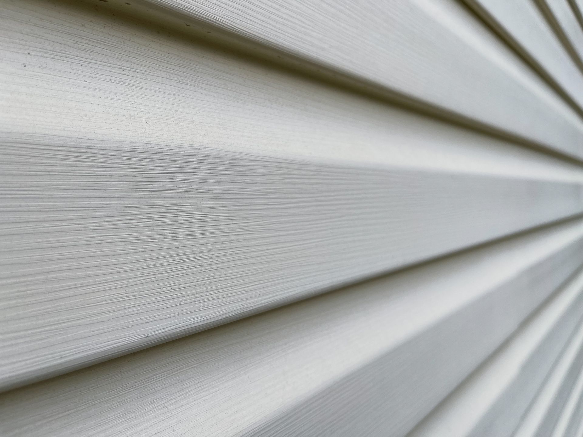 A close-up of white siding on a house, showcasing the texture and detail of the material.