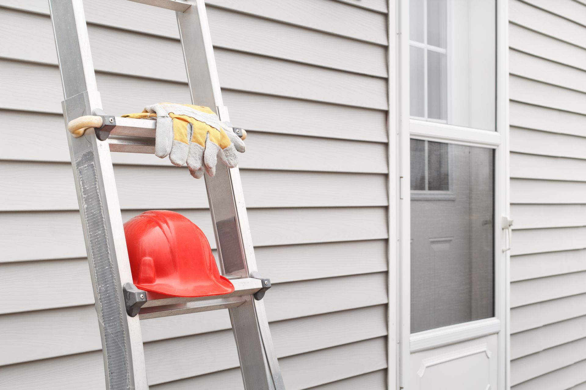 Roofing contractor in a tool belt kneeling on a shingle roof and installing new shingles at sunset. Roofing contractor in a tool belt kneeling on a shingle roof and installing new shingles at sunset.