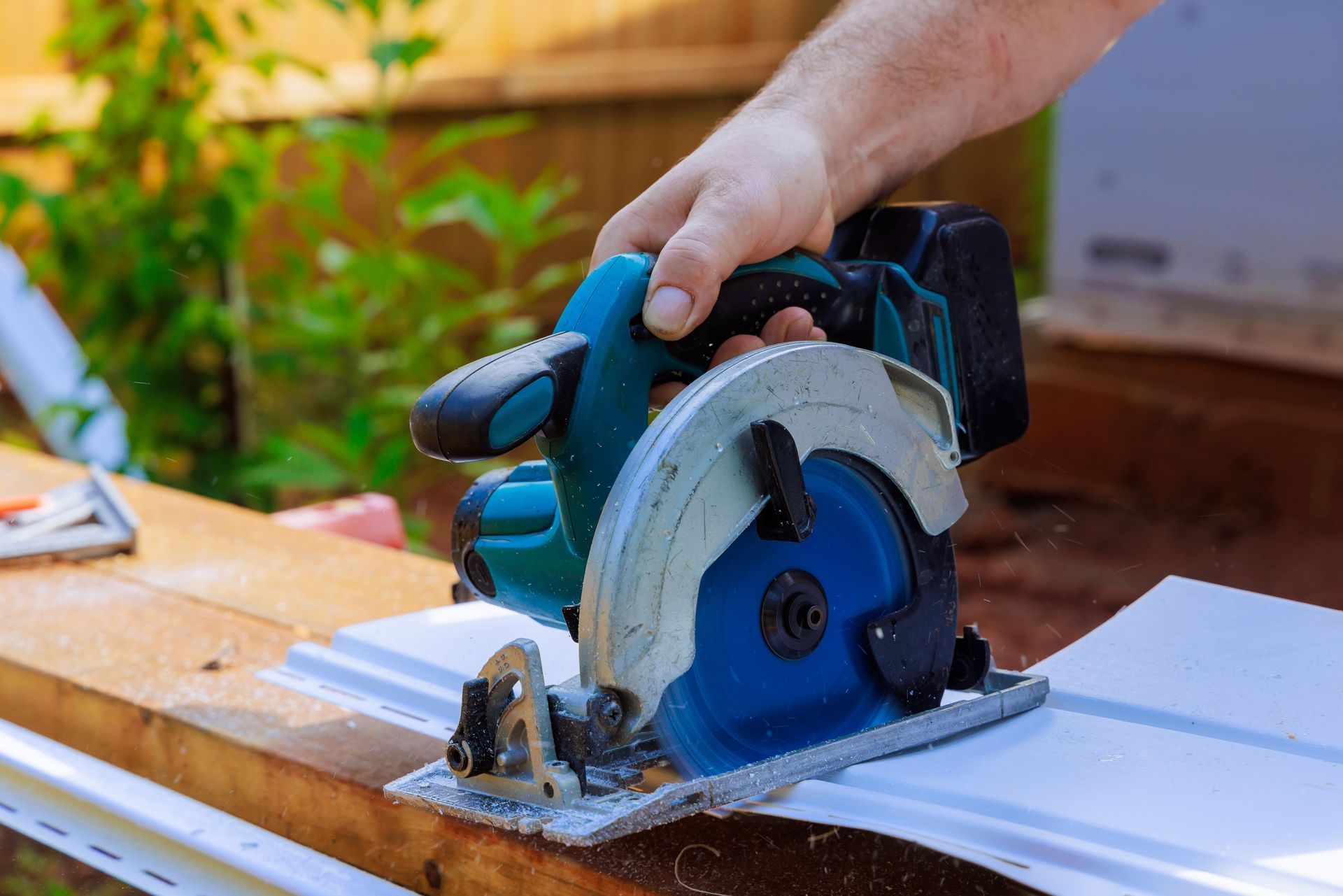 A man operates a circular saw, cutting through a piece of siding with focused concentration A man operates a circular saw, cutting through a piece of siding with focused concentration