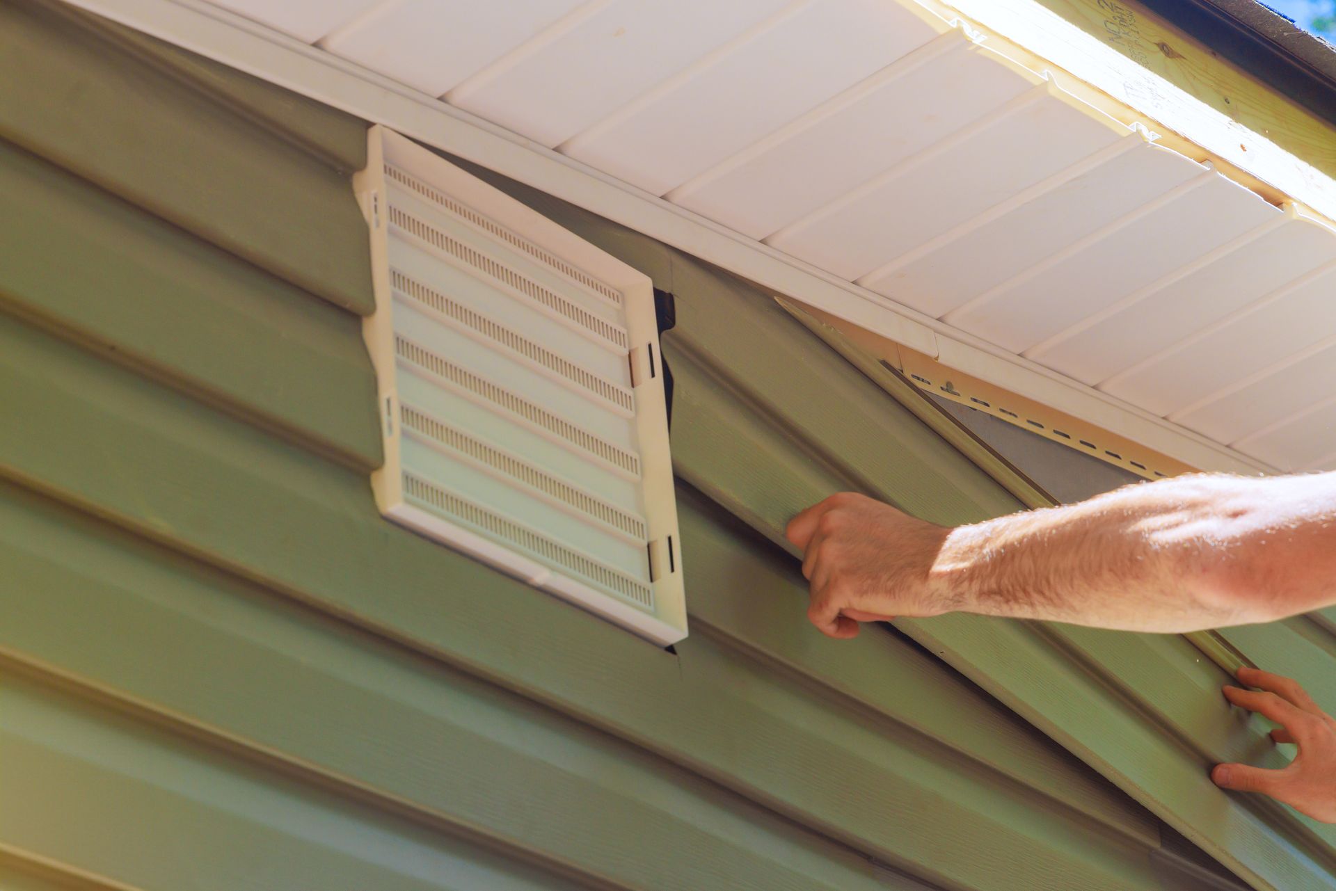 A partial view of a man carefully installing siding in a house.