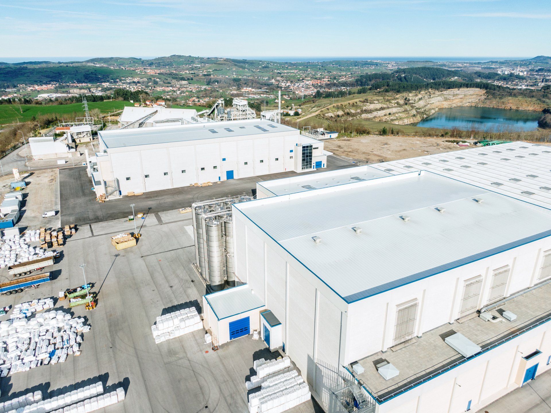 Aerial view of white warehouse buildings in an industrial area with roads and fields in the distance