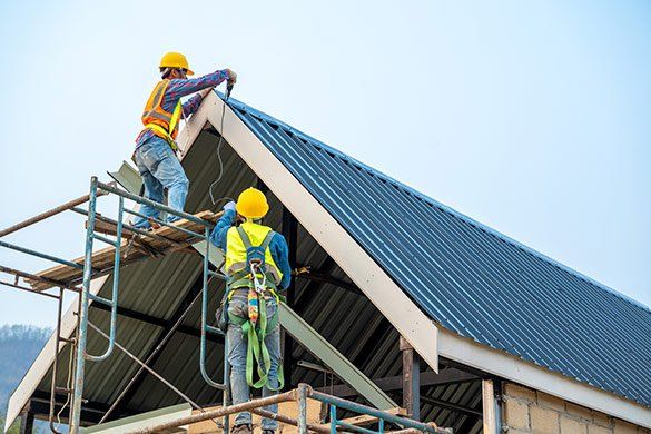 Men Drilling On Metal Roof — Beaver Damn, WI — Heimerl Corporation Men Drilling On Metal Roof — Beaver Damn, WI — Heimerl Corporation