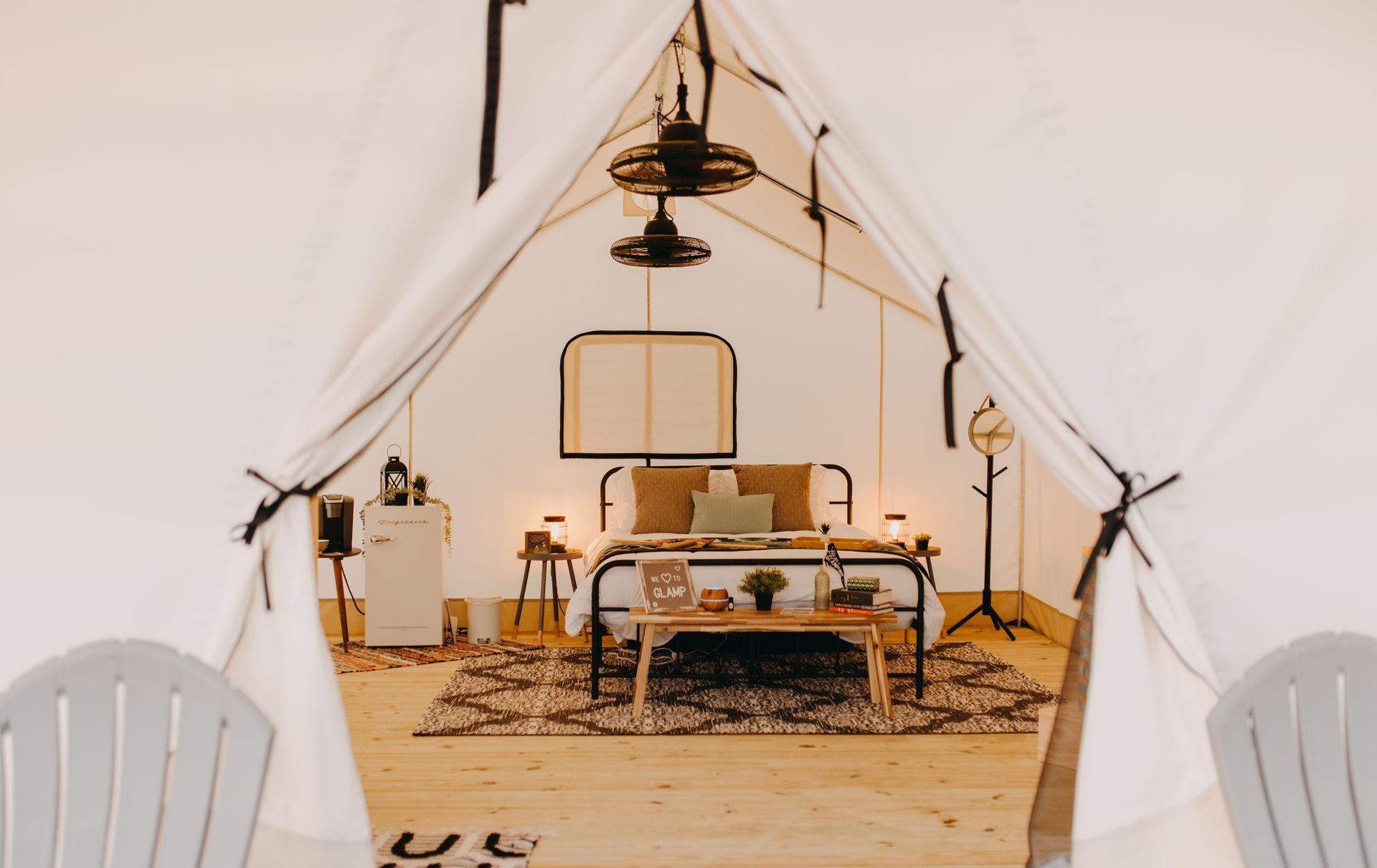 Open tent interior, a bedroom with bed, rug, and furniture.