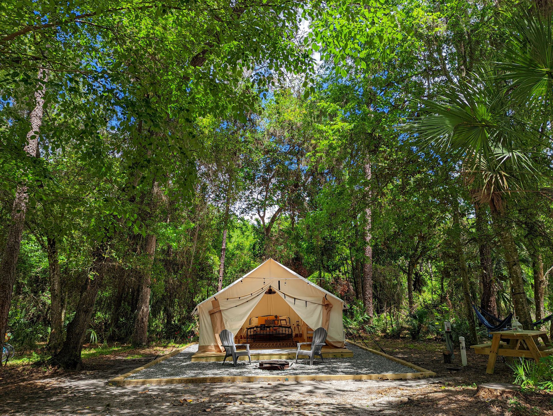 Canvas tent set up in a wooded area with a picnic table nearby.