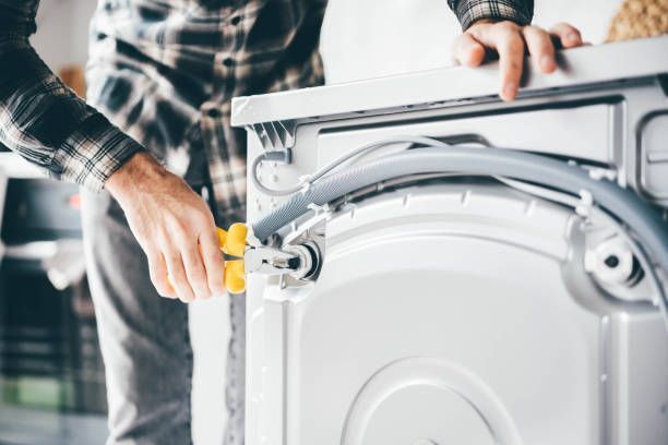 A man is fixing a washing machine in a bathroom.