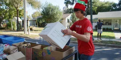 A man wearing a santa hat is loading boxes into a cart.