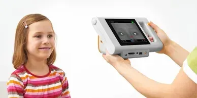 A person is holding a tablet in front of a little girl.