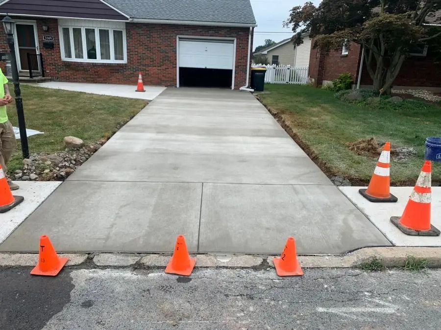 Concrete driveway under construction with orange traffic cones leading to a garage