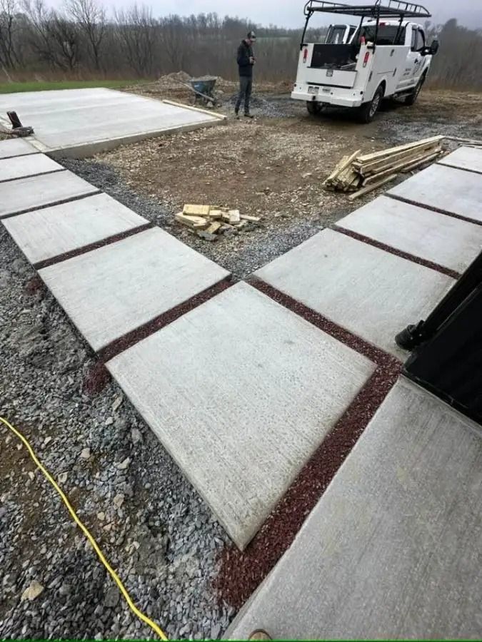 Concrete walkway slabs under construction beside a white utility van on a gravel site
