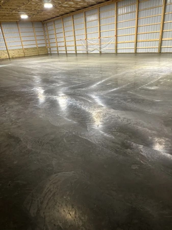 Empty warehouse interior with a polished concrete floor and tall white walls with exposed framing.