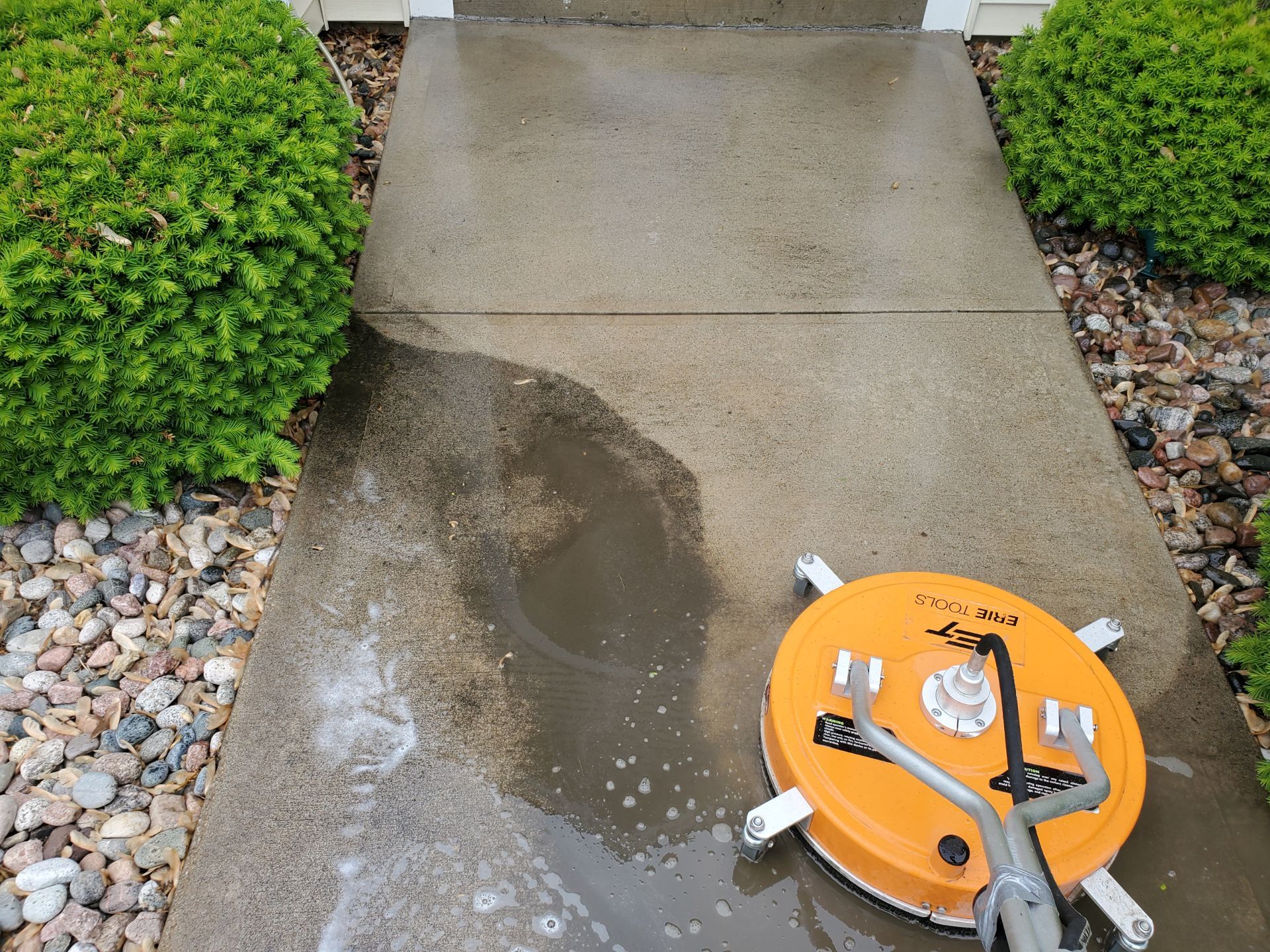 Pressure washer cleaning a concrete sidewalk.