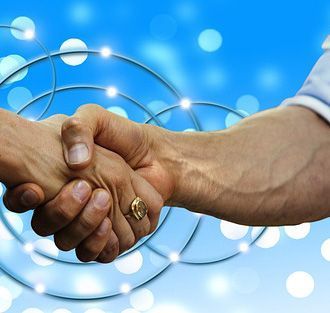 Two hands shaking in a business deal, with a blue network graphic background.