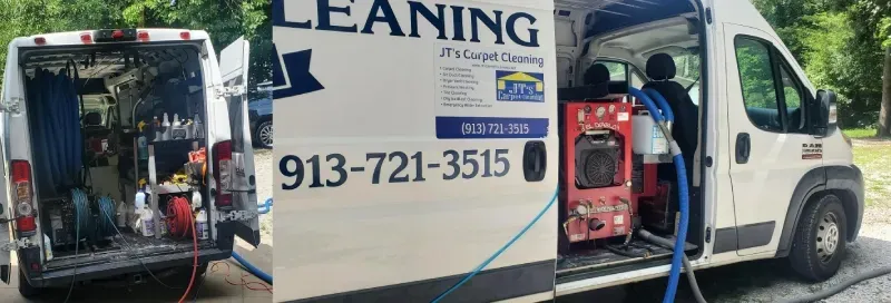 A white carpet cleaning van with open doors, displaying equipment and contact information.