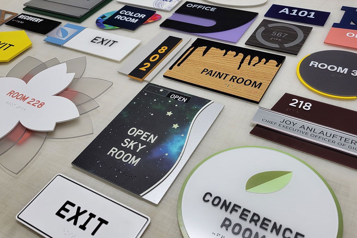 Assorted colorful room and directional signs with text in various shapes and sizes.