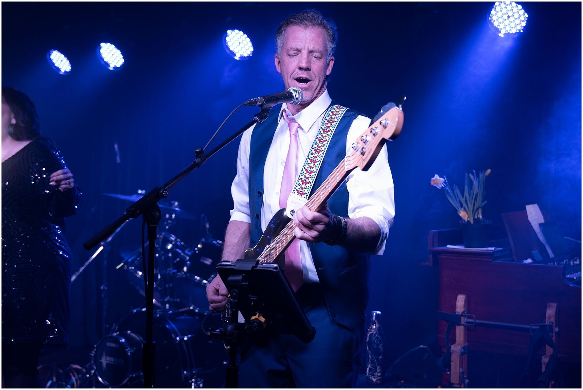 Man playing guitar and singing on stage under blue lights.