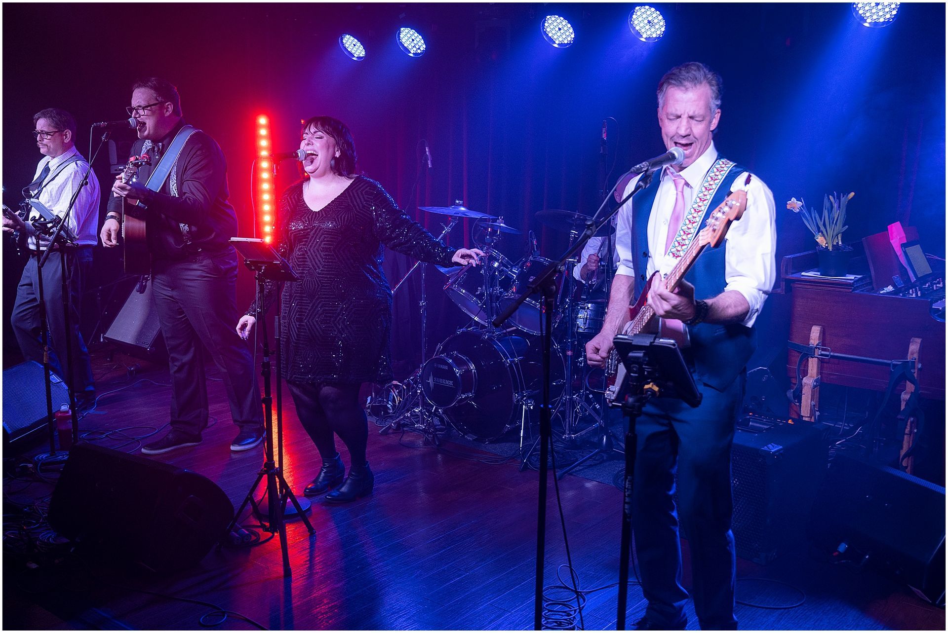 Band performing live on stage under blue and red lights.