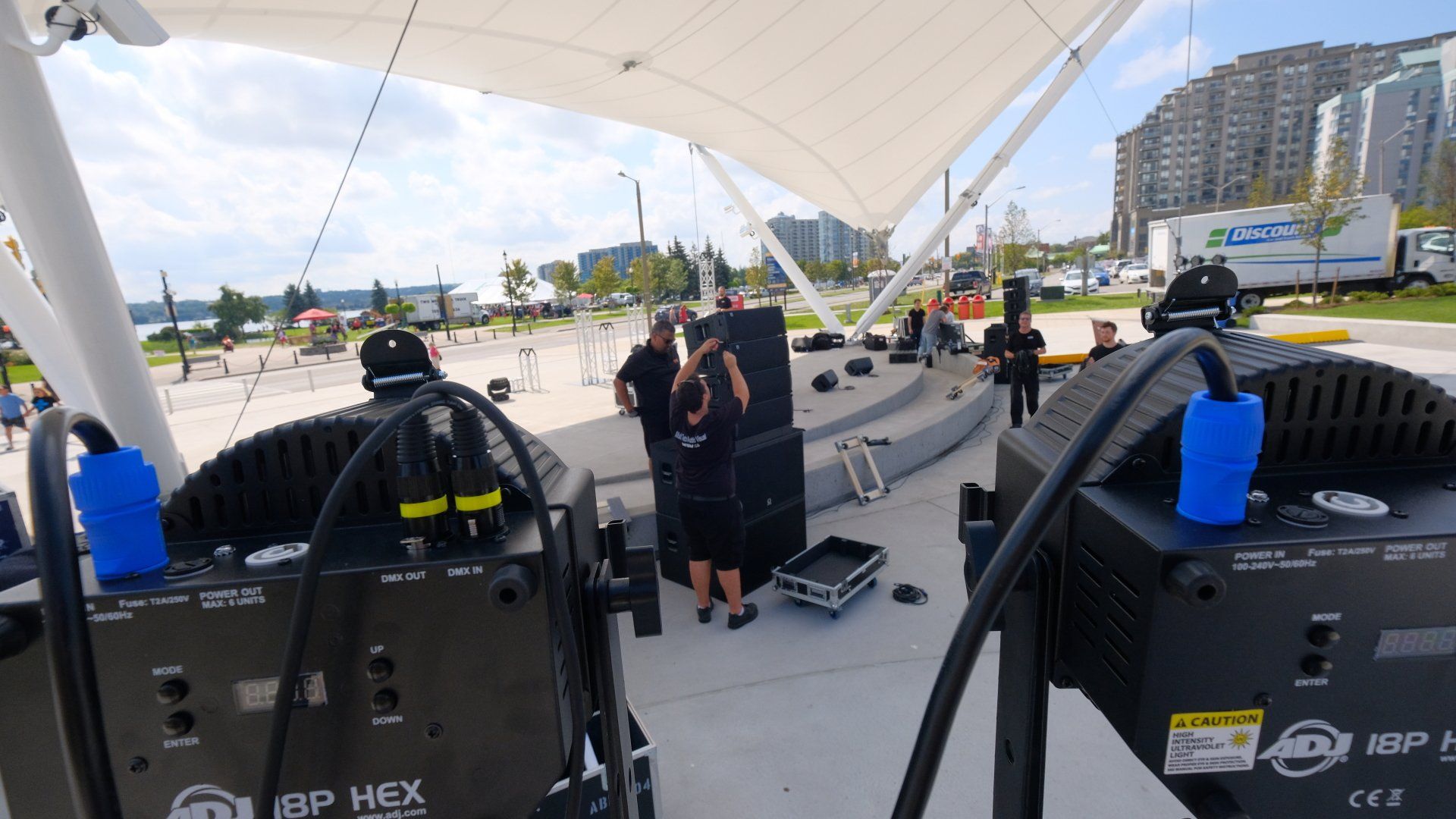 Outdoor stage setup with lighting equipment and crew members preparing for an event.