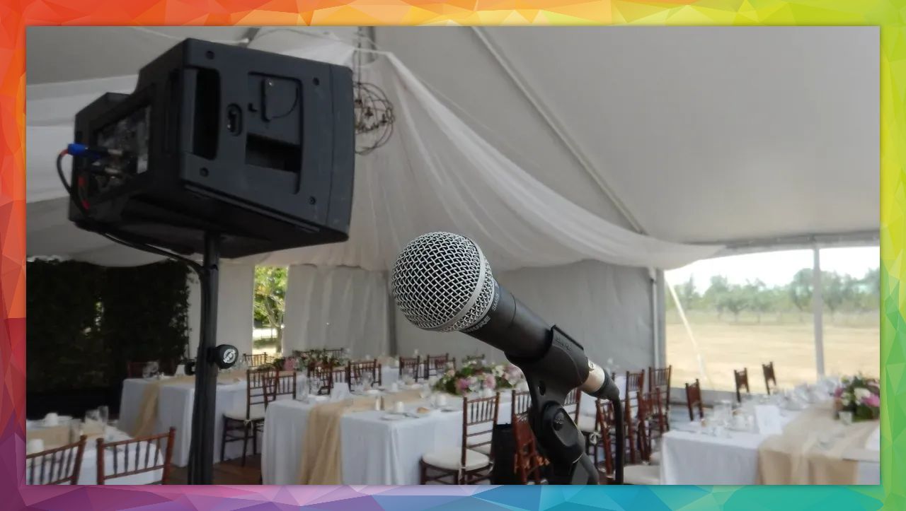 Microphone and speaker set up in tent for wedding reception. Tables set with decorations and seating.