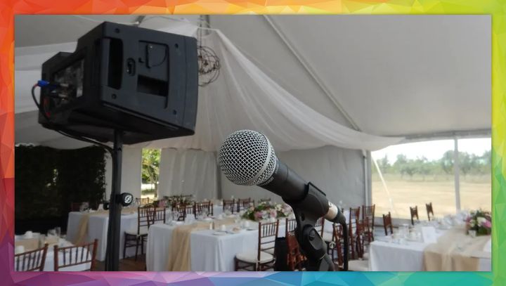 Microphone and speaker set up in tent at an event with decorated tables.