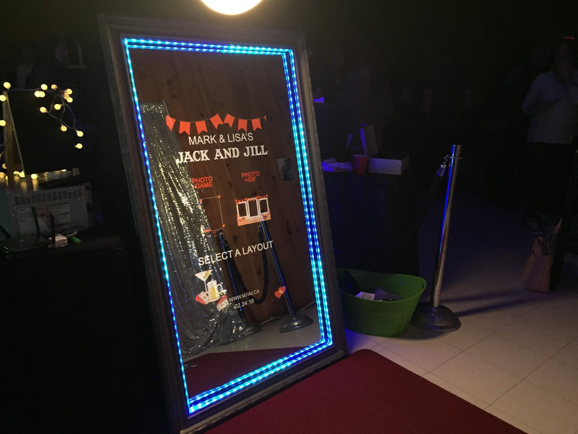 A photo booth mirror with blue LED lights, a red carpet, and a custom graphic for 