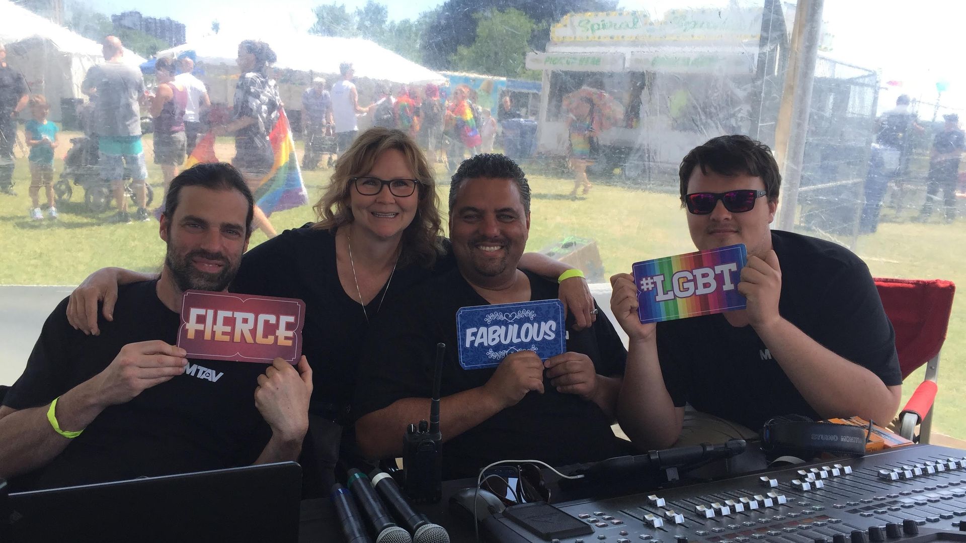 Four people at an outdoor event holding signs: 