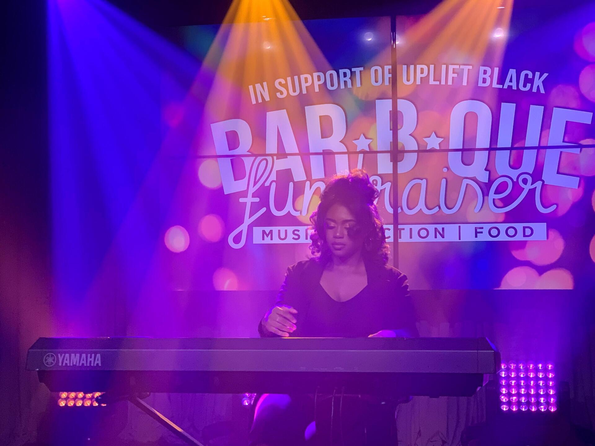 Woman playing a Yamaha keyboard onstage at a fundraiser. 