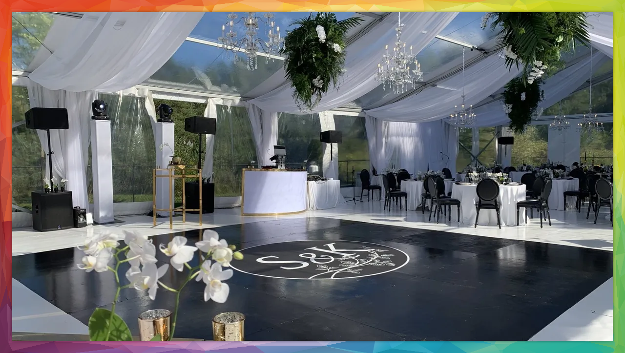 Clear tent wedding reception with black dance floor, white draping, and tables set for guests.