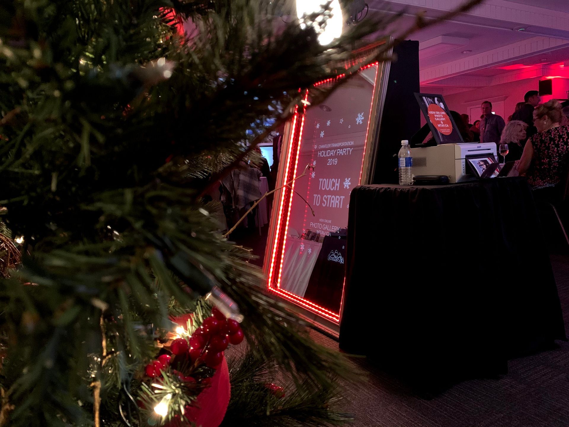 Christmas tree with party scene in background; large sign with red lights.