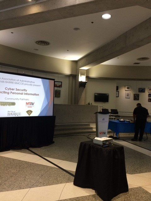 Presentation setup: projector on table, screen with title 