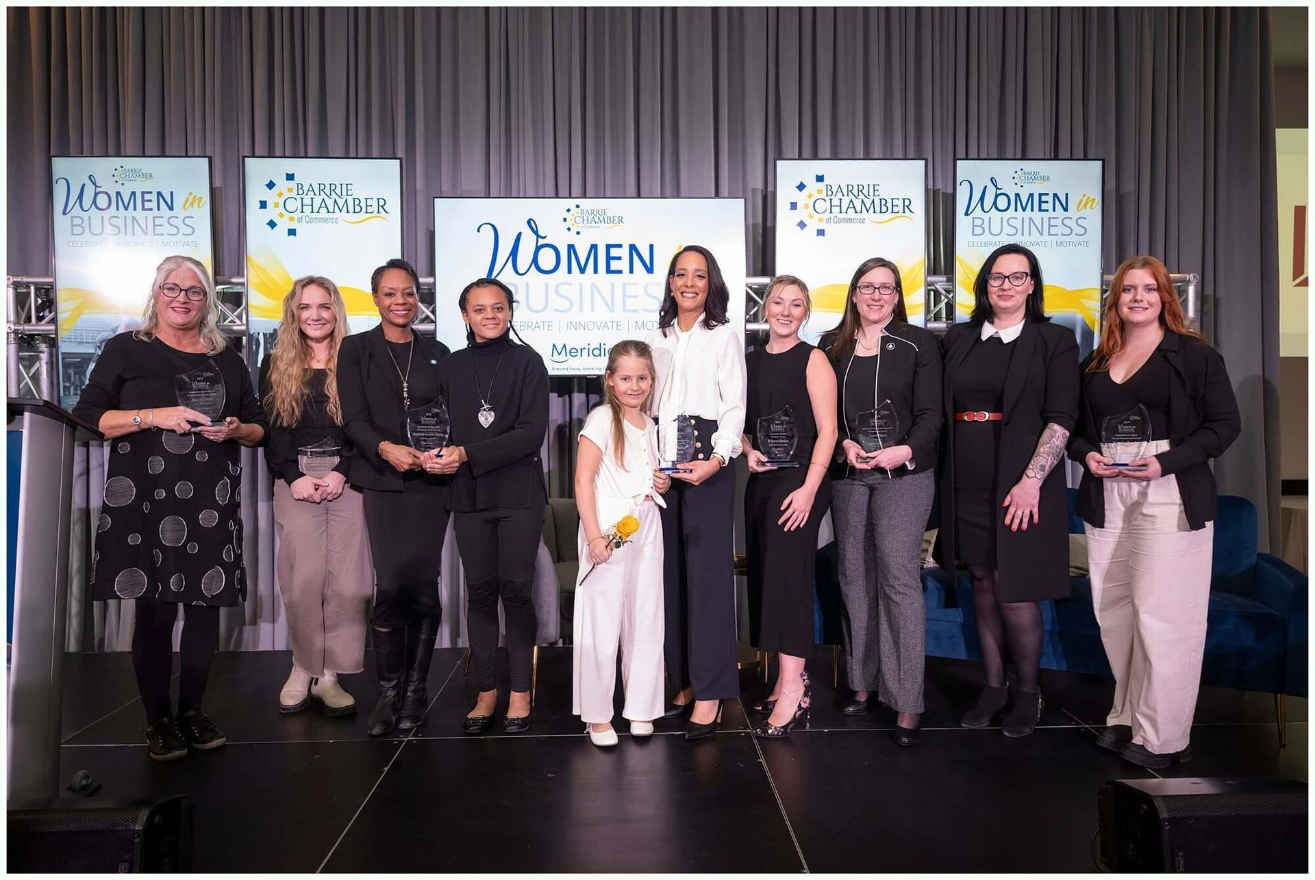 Group of women holding awards on stage with a 