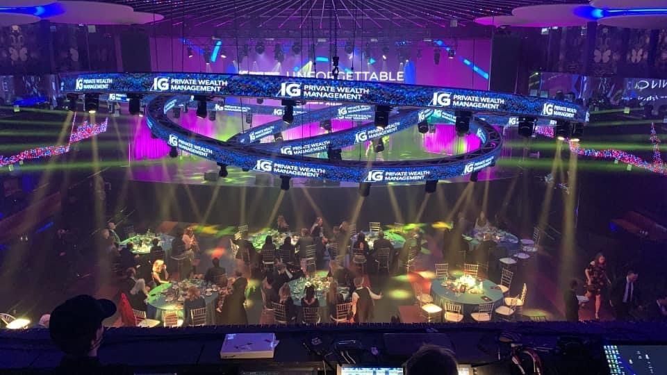 Event stage with musicians performing; large, lighted sign above.