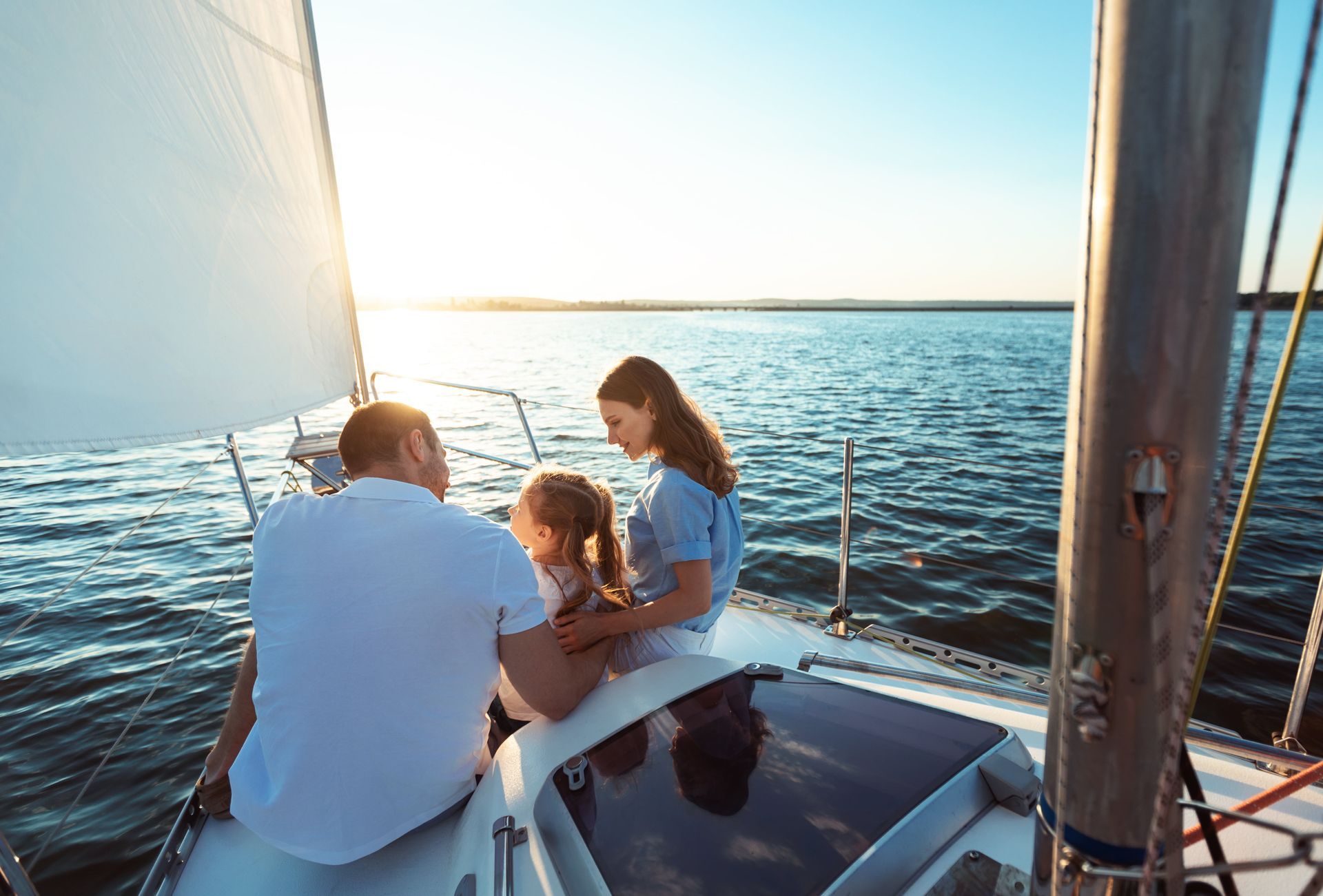A family is sitting on a sailboat in the water.