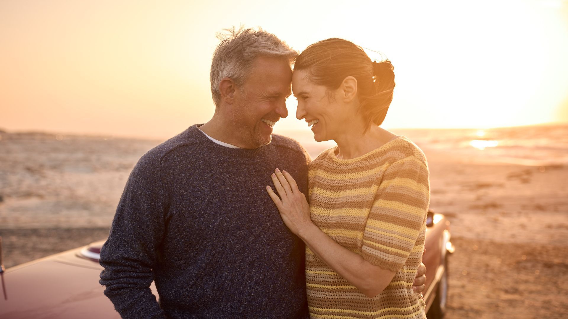 A man and a woman are standing next to each other on the beach.