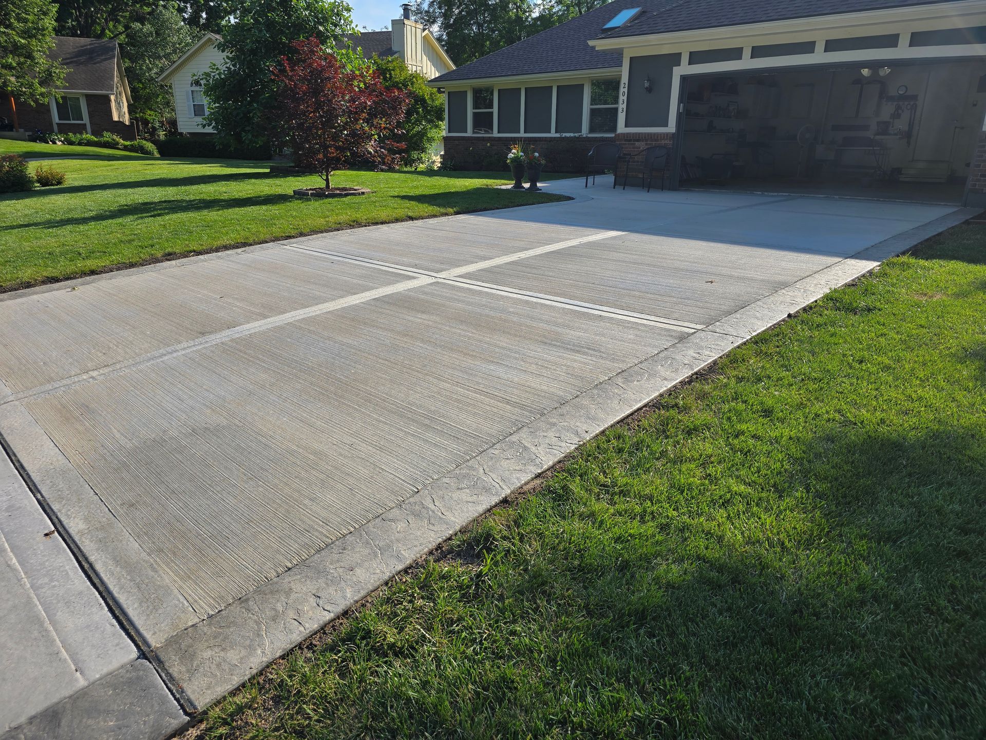 Concrete driveway with white basketball hoop lines beside a house