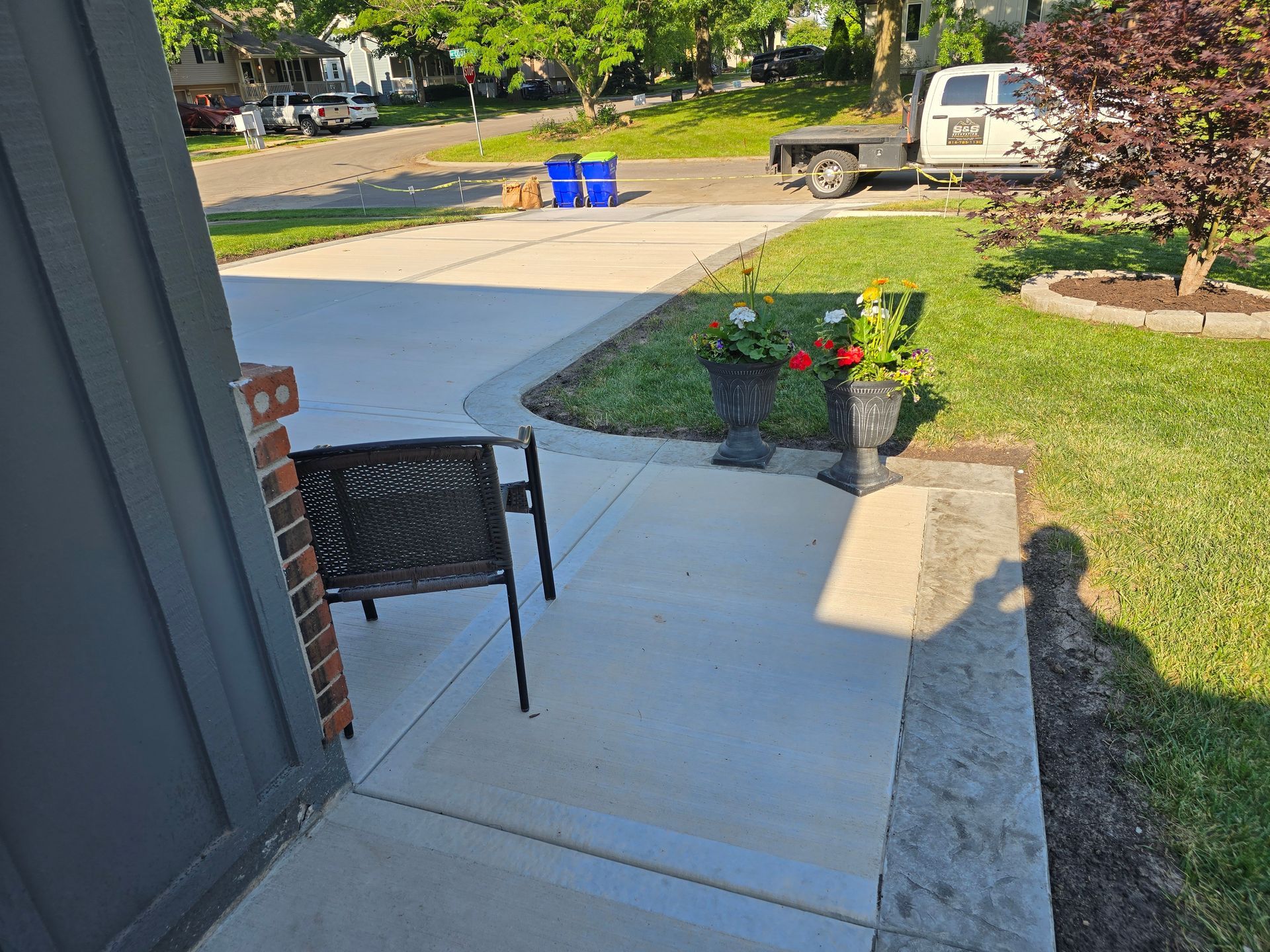 concrete driveway and front porch walk way with a black chair