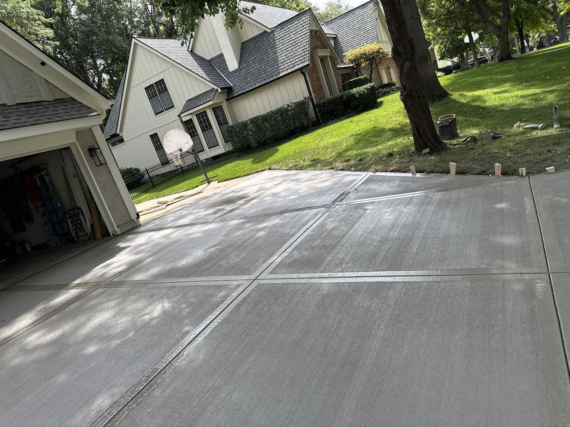 Freshly poured concrete driveway beside a suburban house and lawn