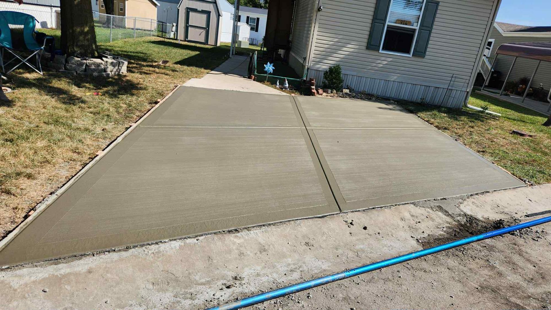 Freshly poured concrete driveway leading to a house