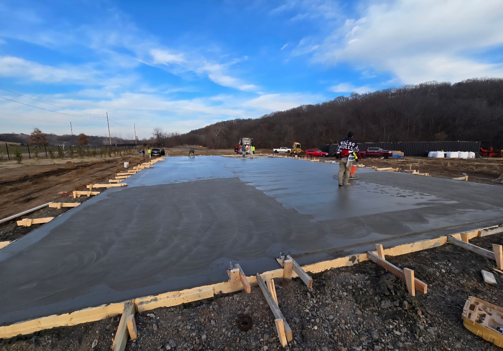 Construction site with workers smoothing a large concrete slab