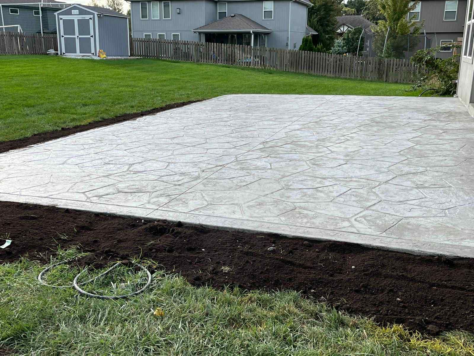 White stamped concrete patio beside a green lawn