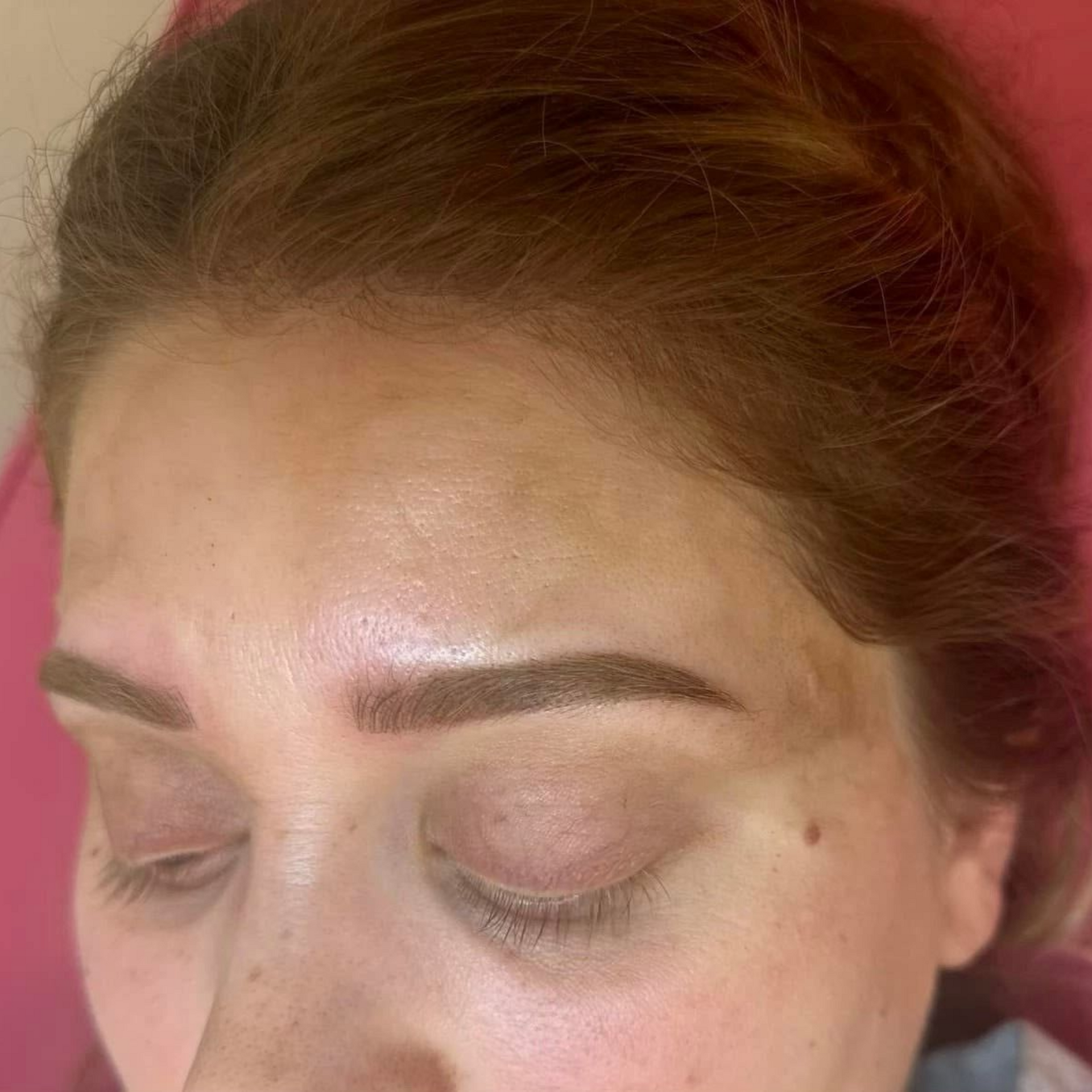 Woman with closed eyes, newly microbladed brown eyebrows, light skin.