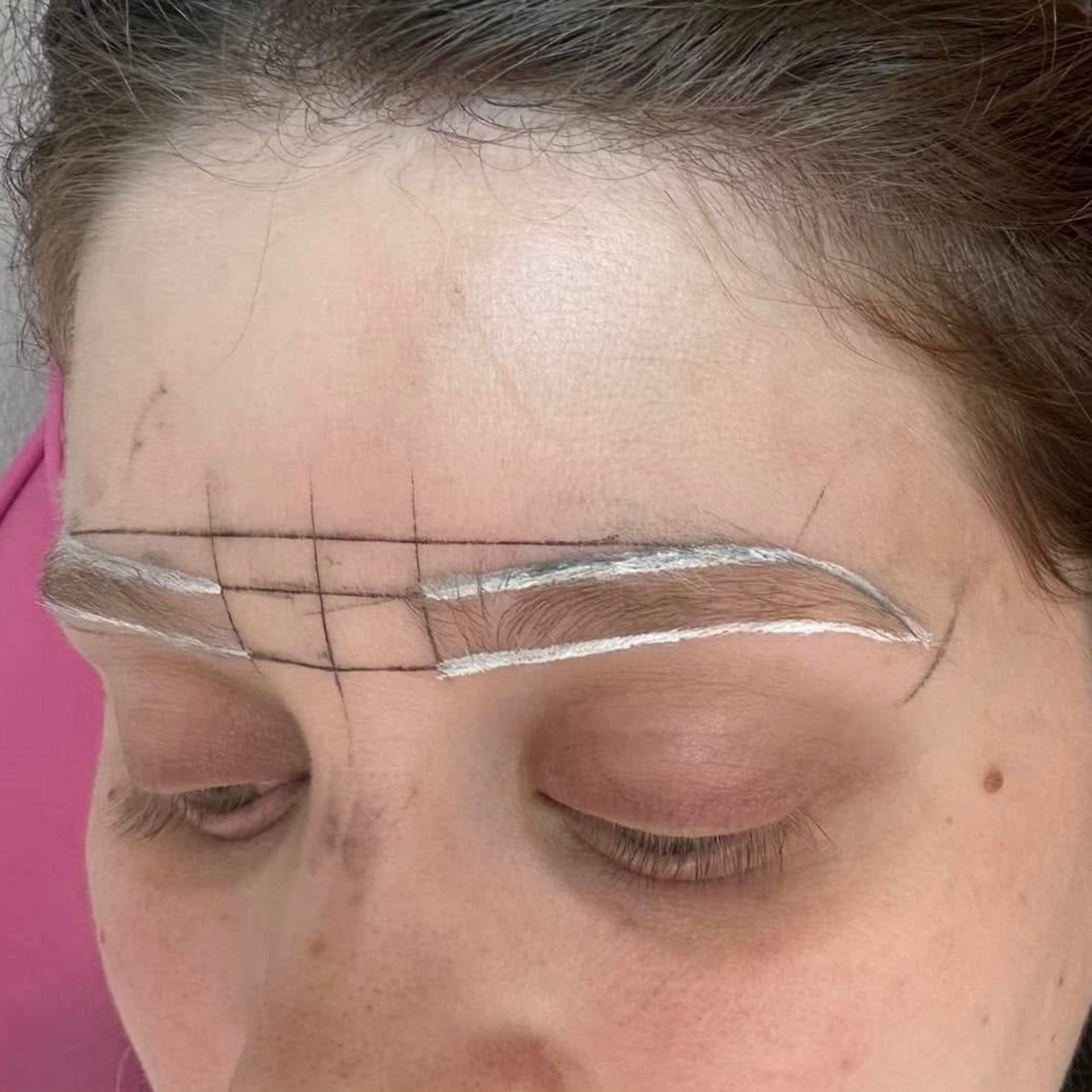 Eyebrows prepped for microblading with white outline and grid.