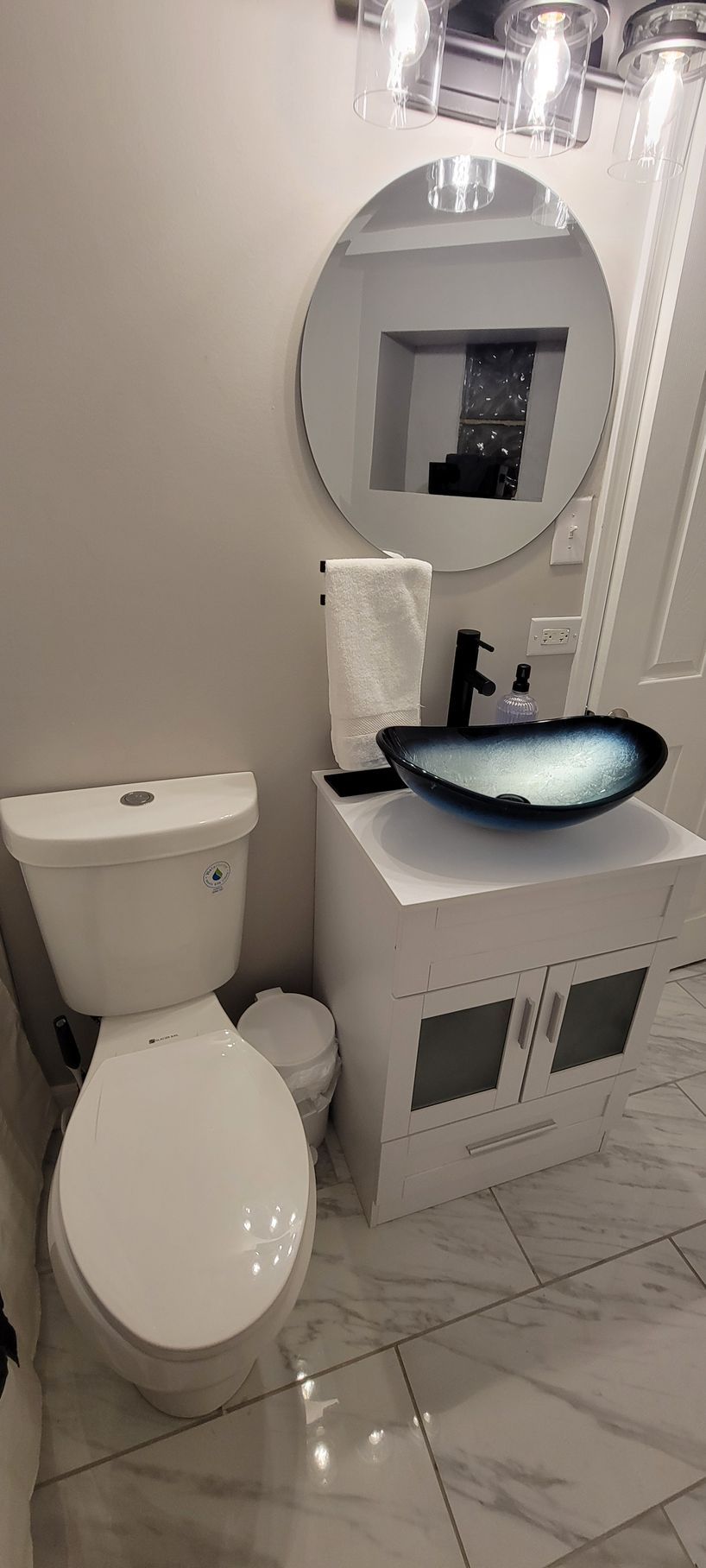 A bathroom with a toilet , sink and mirror.